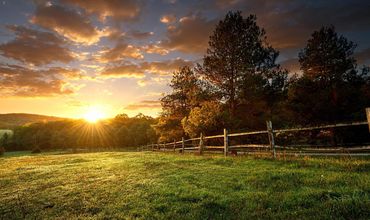 Fazenda e sítio com cercado e paisagem do pôr do sol.