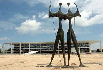 Obra "Os Dois Candangos" com vista para o prédio do Poder Executivo na Praça dos Três Poderes, cidade de Brasília - DF.
